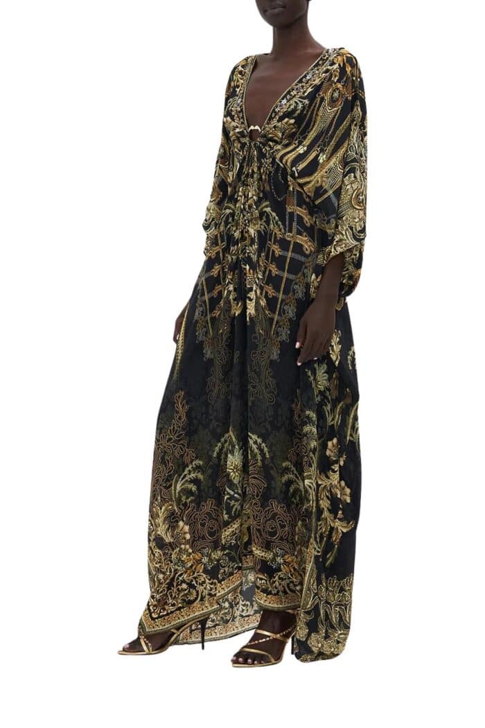 Side view of long silk kaftan on model from Camilla in black based print with gold highlights and hardware.